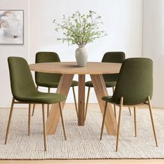 a wooden table with green chairs and a white vase on top of it in a room