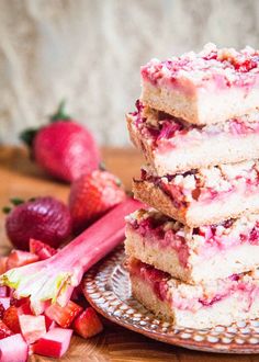 a stack of strawberry shortcakes sitting on top of a plate next to sliced strawberries