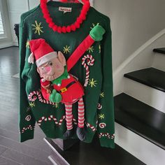 an ugly christmas sweater hanging on the wall in front of some stairs with candy canes