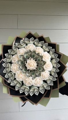 a paper flower made out of money is hanging on the wall in front of a white brick wall