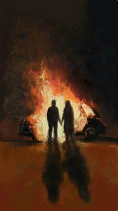 two people standing in front of a fire with a car on the road behind them