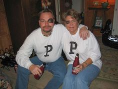 two people are sitting on the floor with beer bottles in their hands and one person is wearing glasses