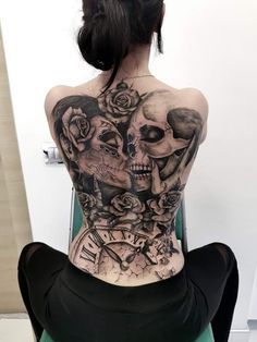 a woman with tattoos on her back sitting in a chair