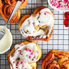 several pastries with icing and sprinkles on a cooling rack