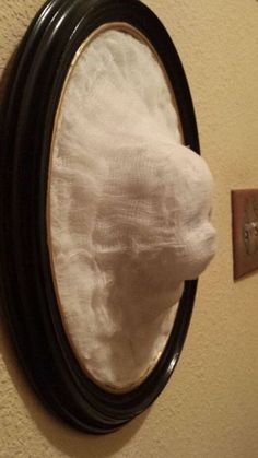 a mirror that is hanging on the wall with a white cloth covering it's face