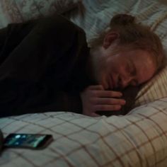 a man sleeping on top of a bed next to a cell phone