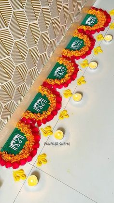 candles are lined up on the floor in front of a wall with flowers and leaves