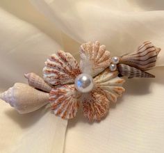 seashells and pearls on white fabric with pearl bead brooch or pin