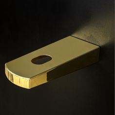 a gold toilet paper holder on a black wall with a hole in the middle that is shaped like a rectangle