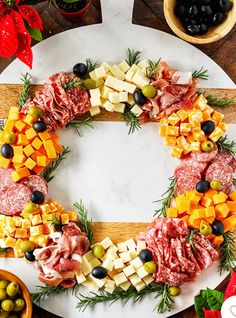 a platter with meats, cheeses and olives arranged in the shape of a wreath