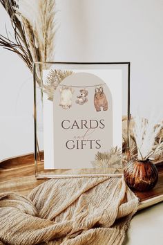 cards for gifts are displayed on a table with dried plants and an acrylic vase