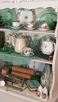 an old china cabinet is filled with green dishes and other items, including teapots