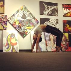 a woman doing a handstand in front of paintings