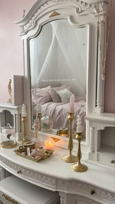 a white dressing table with a mirror and candles on it