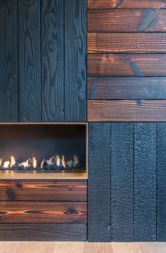 the fireplace is built into the side of a wooden wall and has several small rocks in it