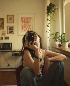 a woman sitting on the floor talking on her cell phone while holding a camera up to her ear