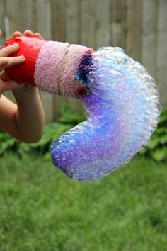 a child holding up a rainbow bubble snake toy in the air with text overlay reading rainbow bubble snakes