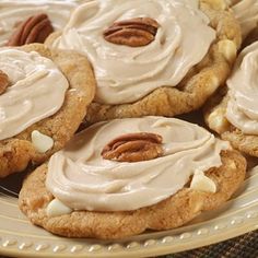 several cookies with frosting and pecans on a plate