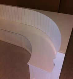 a white curved bench sitting on top of a carpeted floor next to a wall