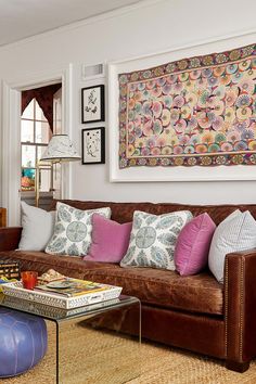 a living room filled with lots of furniture next to a painting on the wall above a coffee table