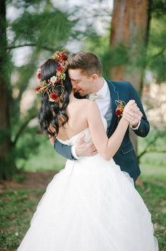 a bride and groom embracing in the woods