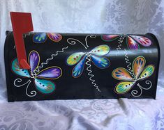 a black mailbox with colorful butterflies painted on the front and sides, sitting on a white background