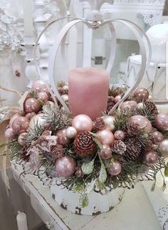 a heart shaped candle is surrounded by ornaments and pineconis on a white table