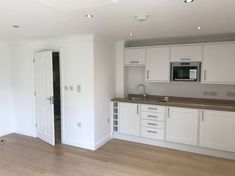 an empty kitchen with white cabinets and wood flooring is pictured in this image from the inside