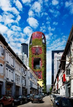 an unusual building with plants growing on it's side in the middle of a city