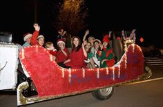 a group of people riding on the back of a red and white truck with christmas decorations