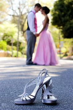 a bride and groom standing next to each other in front of trees with their wedding shoes on the ground