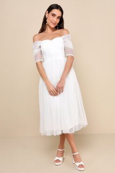 a woman wearing a white dress with sheer sleeves and an off the shoulder neckline