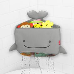 a gray whale shaped storage bag filled with toys in a white tiled bathroom shower stall