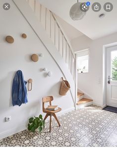 there is a coat rack on the wall next to a chair and some plants in front of it