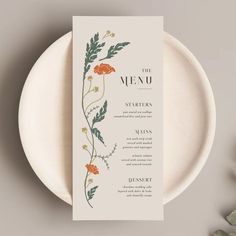 the menu card is sitting on top of a white plate with orange flowers and green leaves