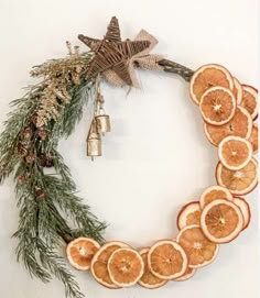 orange slices arranged in the shape of a wreath with bells and pine cones on top