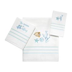 two white towels with fish and starfish embroidered on the front, one in blue