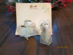 two small white angel figurines sitting on top of a wooden table