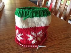 a knitted christmas stocking sitting on top of a wooden table