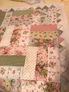 an old quilt is laying on top of a tablecloth with flowers and gingham