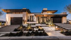 a modern house is lit up at night in the desert with cactus and succulents