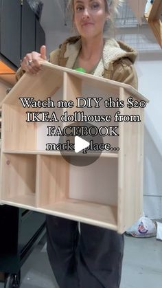 a woman holding up a dollhouse made out of plywood planks with the caption, watch me diy this $ 50 ikea dollhouse from facebook mark place