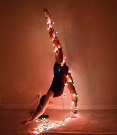 a woman is doing a handstand on the floor with lights all around her