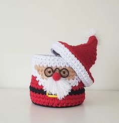 a crocheted santa clause hat on top of a small bag with a red nose