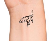 a small turtle tattoo on the wrist with bubbles coming out of its mouth and head