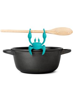 a blue crab in a black pan with a wooden paddle sticking out of it's back