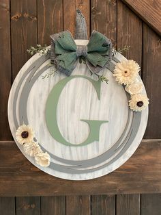 a wooden sign with flowers and a bow on it