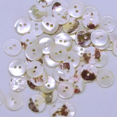 many different types of buttons on a white surface with holes in the middle and bottom