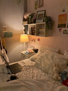 a laptop computer sitting on top of a bed next to a stuffed animal and lamp