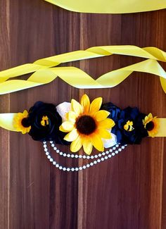 a headband with sunflowers, pearls and ribbons attached to it on a wooden surface